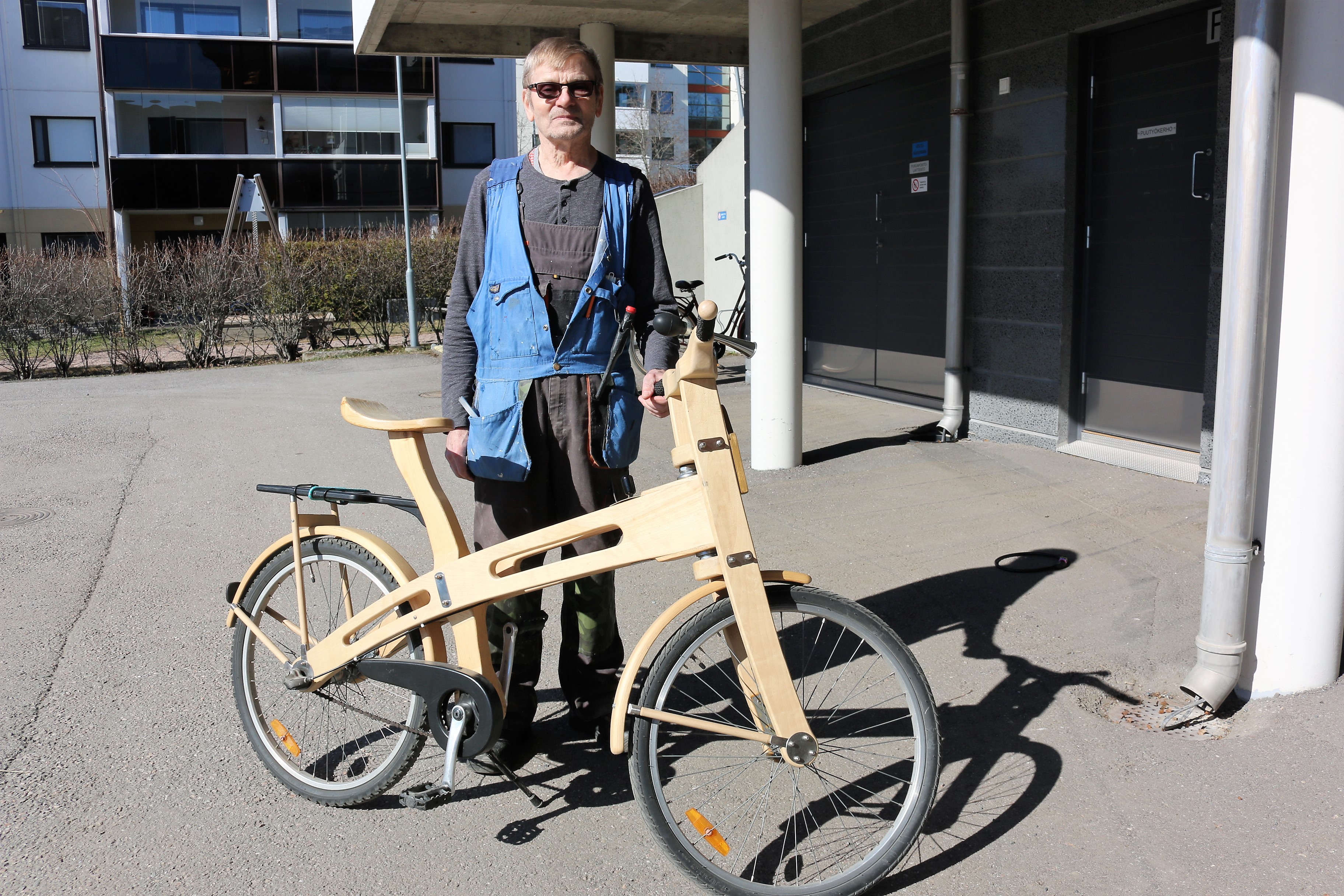 Pekka Jääskeläinen seisoo puurunkoisen pyöränsä takana Kirkonkulman alaparkkipaikalla