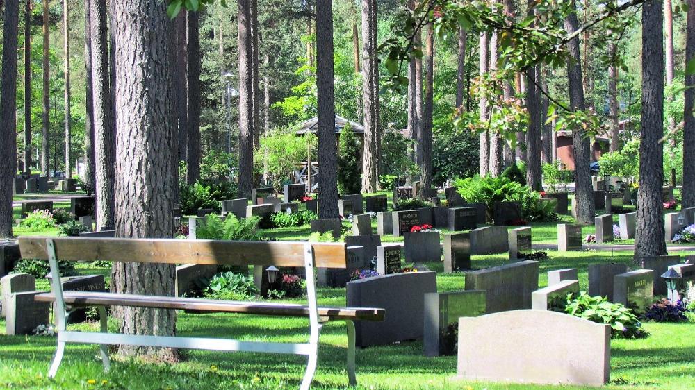 Kesäinen kuva Järvenpään hautausmaalta. Penkki ja hautoja.